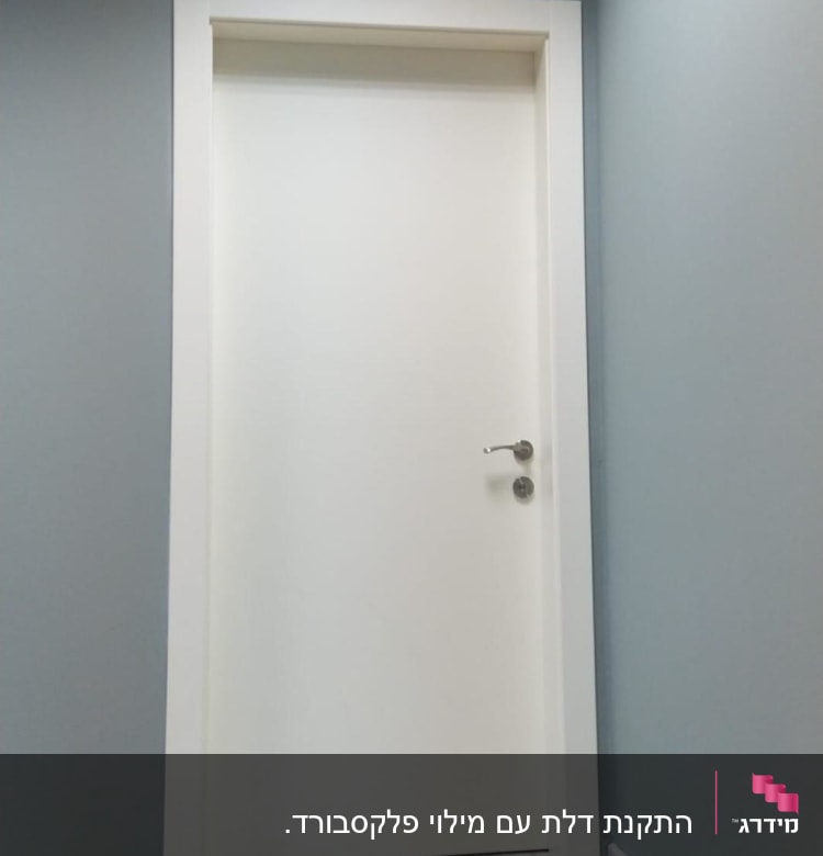 דלת לבנה עם ידית מתכת על קיר אפור